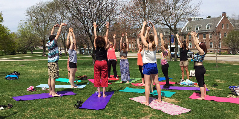 students doing yoga on Thompson Hall lawn