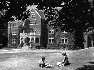 Smith Hall with students two students socializing on lawn, taken by R.Merritt, 1965.