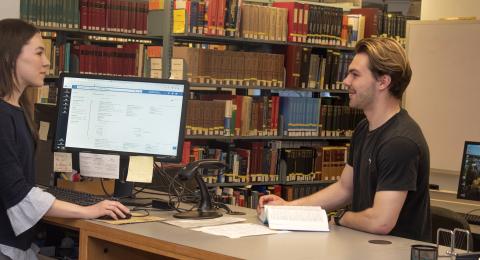 Student worker talking to another student at the Chemistry library desk