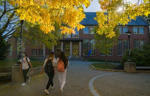 Students walking in front of Dimond Library with fall foliage