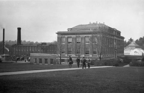 Men walking on a sidewalk between DeMeritt Hall and Thompson Hall in 1924