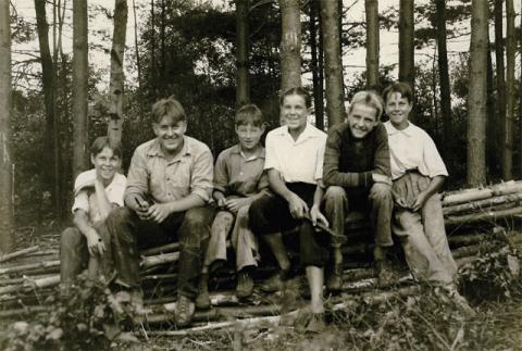 children sitting on logs in the woods
