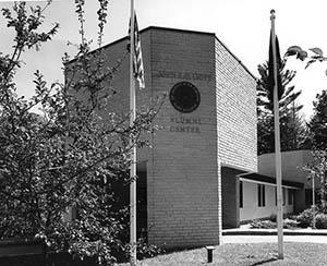 Elliott Alumni Center entrance with flags in the foreground, ca. 1970s.