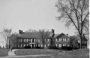 Hood House from the front lawn with man walking on walkway.