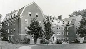 Scott Hall from front lawn with trees in foreground.