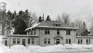 Taylor Hall with snowdrifts in foreground and UNH water tank in background, taken by Clement Moran in February 1935.