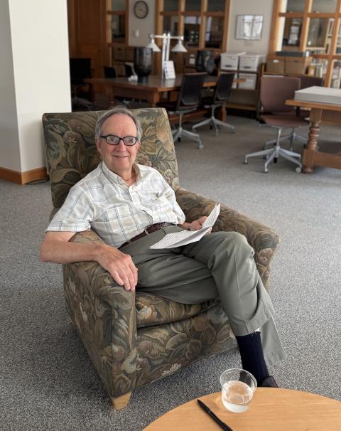 Professor Emeritus John Carroll sitting in the University Archives reading room in Dimond Library